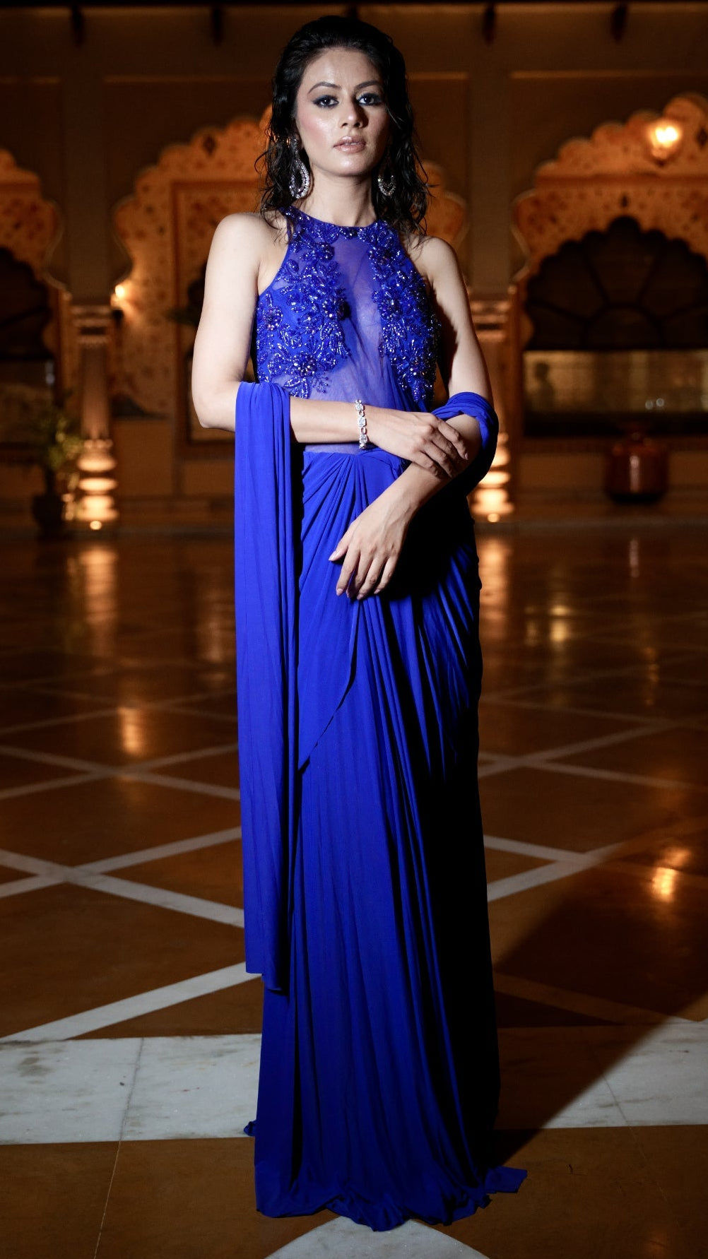 Woman in a blue saree standing in an ornate indoor setting