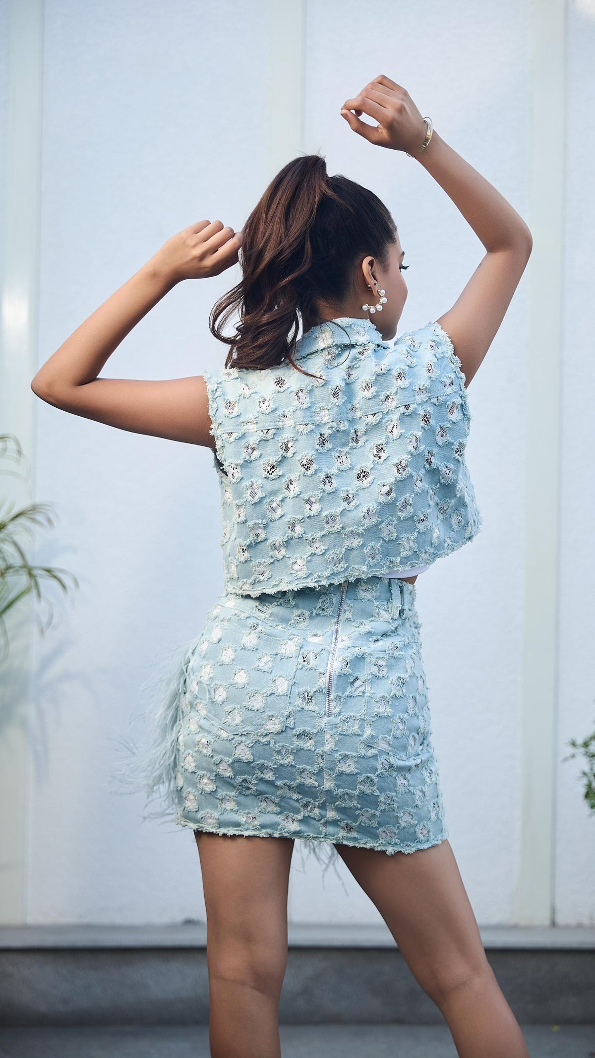 Woman in a light blue floral dress posing outdoors with plants in the background