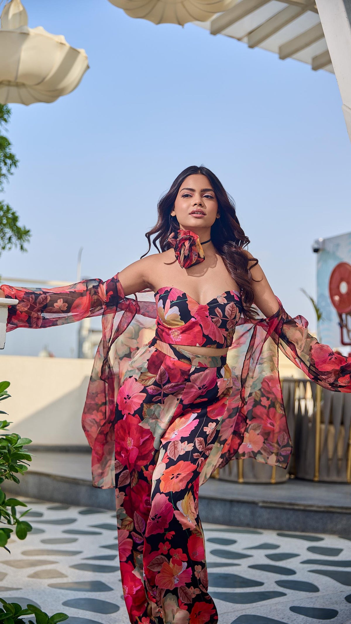 Woman in a floral outfit standing outdoors with a clear sky background