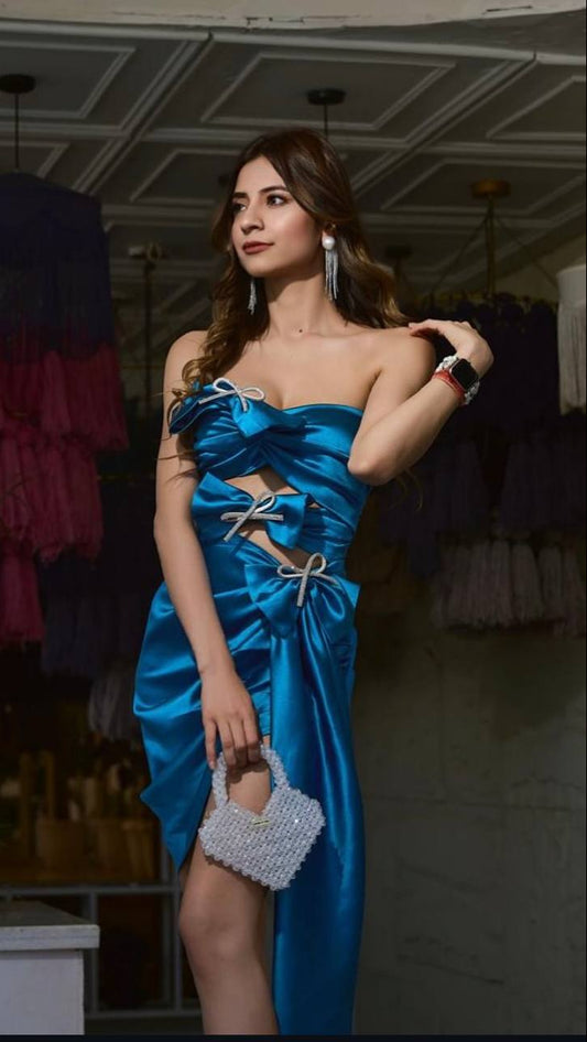 Woman in a blue dress holding a silver handbag in an indoor setting