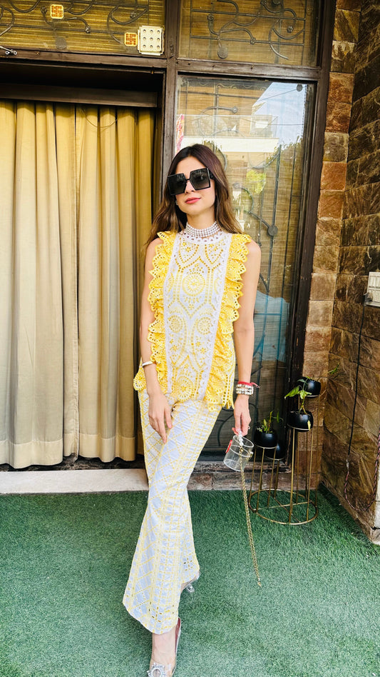 Woman in a yellow and white outfit standing in front of a building entrance.