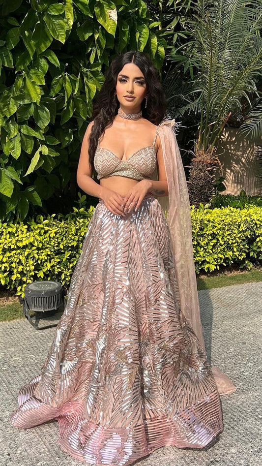 Woman in a sparkling outfit standing outdoors with greenery in the background