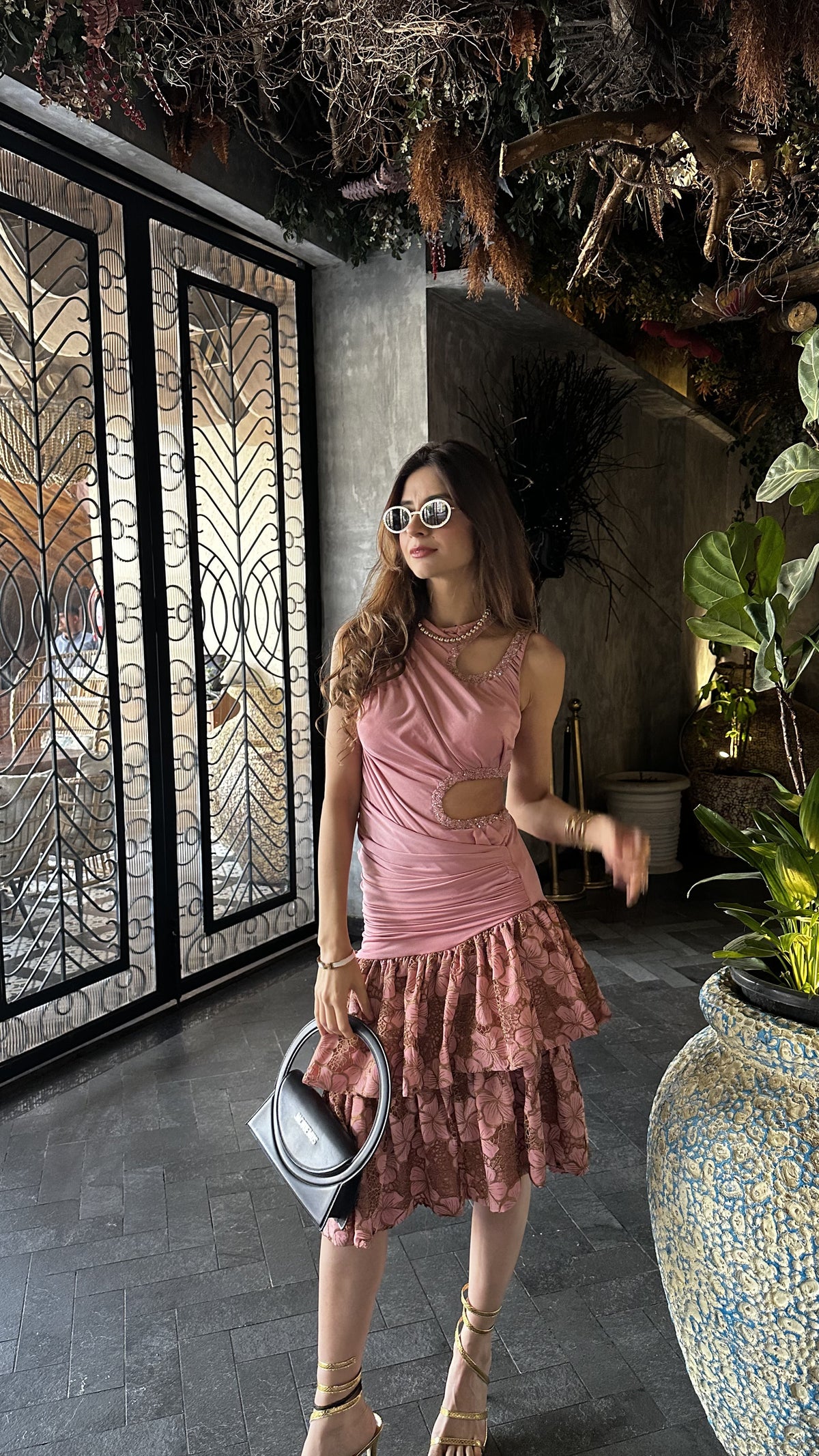 Woman in a pink dress standing in an indoor setting with decorative elements.